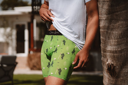 Person wearing green boxer briefs with a golf design, standing outdoors.
